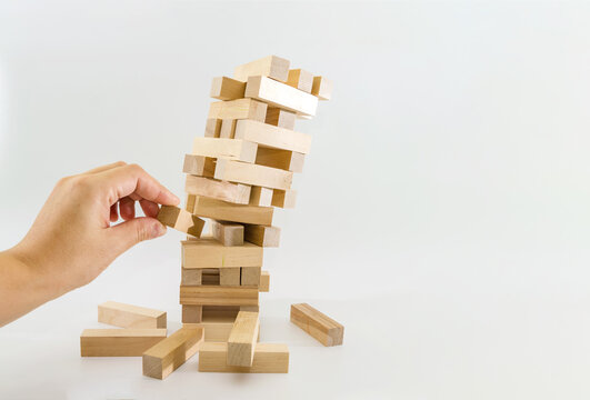 Tower of wooden blocks and human hands take one block. planning, risk and strategy in business. at the risk of taking a wooden block from the tower.