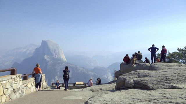 Tourists at a Glacier Point vista in Yosemite National Park.  Half Dome and the Sierra Nevada Mountains in the distance.