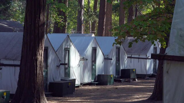 Model Released camper walks through the a row of white canvas tents at Curry Village, Yosemite Valley National Park, California.