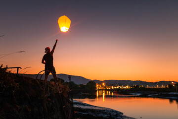 Teenager flying a chinese lantern at sunset time. © Jorge Argazkiak