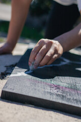 Latin hispanic woman with colorful hair painting a wooden board with black and white paint. Outdoors painting hobbie
