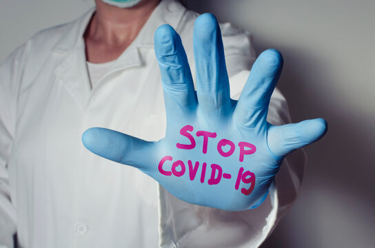 Healthcare worker with Stop Covid-19 text written on safety glove. Wearing masks and gloves to protect yourself against coronavirus.
