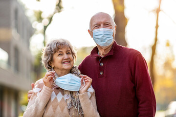 Portrait of senior couple wearing protective face masks outdoors 
