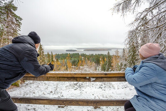 A man and a woman on the observation tower, look at the winter, landscape. Forest in the snow and the sea in the distance