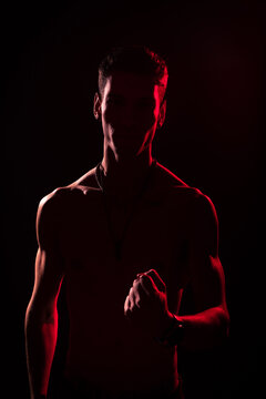 Young Adult Illuminated By Red And White Lights With A Black Background.