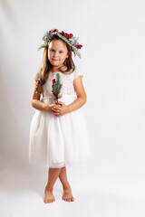 full-length portrait of a girl in a white Princess dress and a Christmas wreath, barefoot, isolated on a blue background.