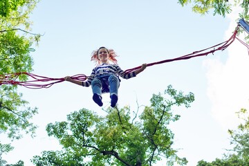 Teenager girl having fun jumping on trampoline with elastic ropes