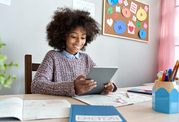 Smiling african kid girl holding digital tablet elearning. Happy mixed race school child using...