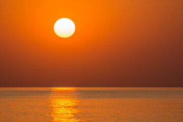 Fototapeta na wymiar warm orange sun on the horizon from the sea during sunrise