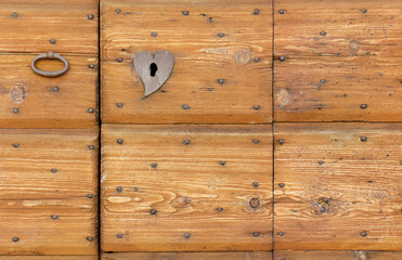 Close-up of an old wooden exterior door with an iron handle and a lock