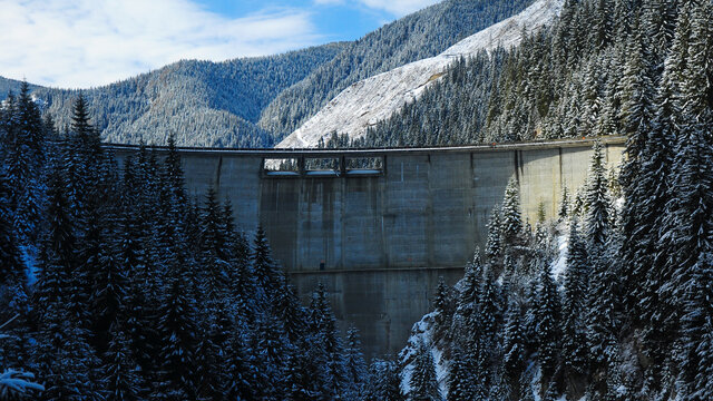 Galbenu Dam during winter time. Snow has covered the wild spruce forests of Capatanii Mountains.