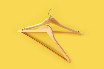 Empty wooden clothes hangers on pastel pink and yellow background. Sale and shopping concept.