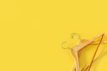 Empty wooden clothes hangers on yellow background with copy space. Sale and shopping concept.