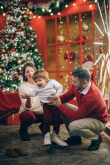 Family with a child near a New Year tree in Christmas decorations