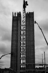 Construction on a large tower block with cranes in black and white