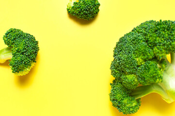 Fresh raw green broccoli on yellow background. Healthy vegetables, diet vegan organic food, vitamins. Creative food concept. Flat lay top view copy space. Broccoli cabbage abstract pattern