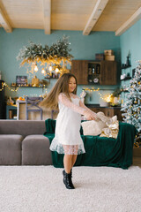 A beautiful seven-year-old girl has fun with a stuffed toy in the living room, decorated for Christmas, in anticipation of the holiday