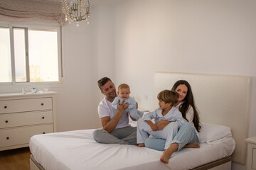 Portrait Of Happy Family Wearing Pajamas In Bed. Family Playing In Bed With Her Children. Family Lifestyle.