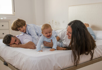 Fototapeta premium Portrait Of Happy Family Wearing Pajamas In Bed. Family Playing In Bed With Her Children. Family Lifestyle.
