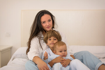Fototapeta na wymiar Mother And Children In Bed Looking At Camera For A Photo. Family Lifestyle