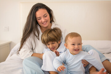 Obraz premium Mom And Children Playing. A Mother And Her Children Play In Bed. Family Lifestyle.