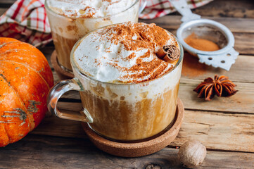 Pumpkin spiced latte or coffee in a glass on a vintage table. Autumn or winter hot drink.