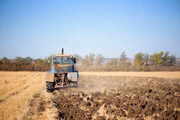 Tractor seeding directly into the stubble after the harvest with blue sky during autumn day.