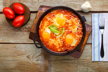Israeli fried eggs shakshuka in a frying pan next to a napkin and a fork. copy space