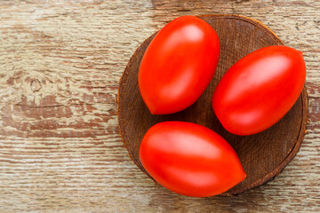 red tomatoes on a round board on a wooden table. horizontal