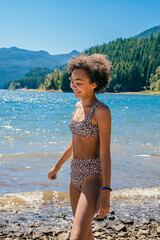 Happy smiling girl in bikini at lake water shore in forest