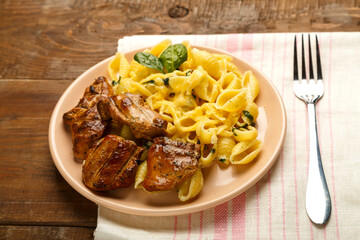 Cheese plate of pasta in a creamy sauce with cheese and chicken on the table on a napkin next to a fork.
