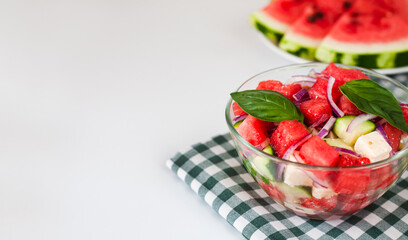 Fresh delicious juicy dietary salad with watermelon, feta cheese, cucumber, red onions and basil leaves on the plate. Close-up. Copy space. Healthy food concept.