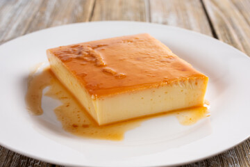 A view of a plate of flan, in a restaurant or kitchen setting.