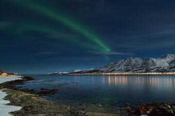 aurora borealis above the Norwegian fjord, reflection of the Lyngen Alps, winter scenery of the Norwegian mountains illuminated by aurora borealis, - 389965487