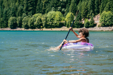 Teen girl paddling on lake in inflatable pool floaty