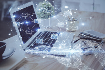 Desktop computer background in office and flying envelops hologram drawing. Double exposure. Electronic mail concept.