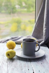 Hot tea in a large cup, lemons and apples on a wooden windowsill, the concept of a vitamin drink for colds, home comfort