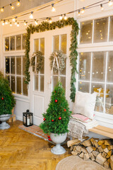 Entrance doors to the house, decorated for Christmas and new year. Trees in vases and Christmas wreaths on white doors