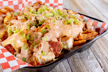 A view of a to-go container of loaded Nashville hot chicken french fries.