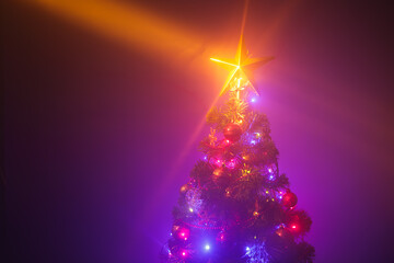 Fototapeta na wymiar Christmas tree with shining star and dense mist