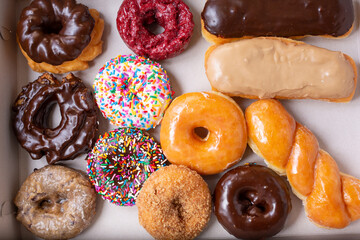 A top down view of a dozen donuts in a cardboard box.