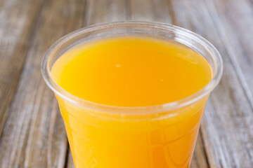 A closeup view of a cup of fresh squeezed orange juice, in a restaurant or kitchen setting.