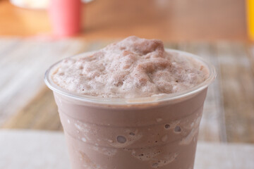 A closeup view of an frozen mocha slushie drink, in a restaurant or kitchen setting.