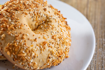 A view of an everything bagel on a plate, in a restaurant or kitchen setting.