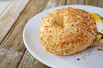 A view of an everything bagel on a plate, in a restaurant or kitchen setting.