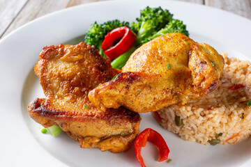 A closeup view of a plate of tandoori chicken and rice.