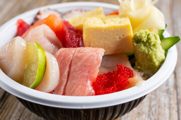 A closeup view of a bowl of assorted sushi ingredients, in a restaurant or kitchen setting.