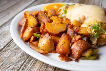 A view of a breakfast plate, featuring roasted potatoes and melted cheese over an omelet, in a restaurant or kitchen setting.