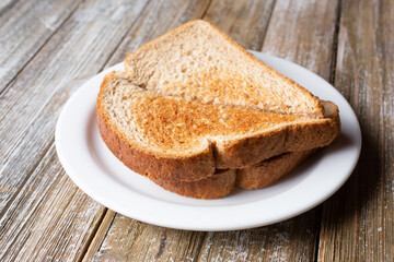 A view of a saucer of wheat bread toast, in a restaurant or kitchen setting.