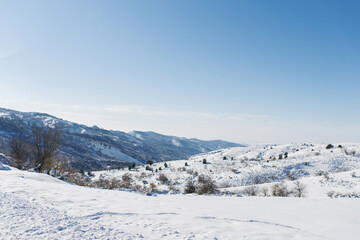 Fototapeta na wymiar First snow in the mountains of Uzbekistan. Winter mountain landscape in clear Sunny weather. Chimgan